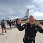 John Payne with with both thumbs up as he is about to board the air plane behind him.