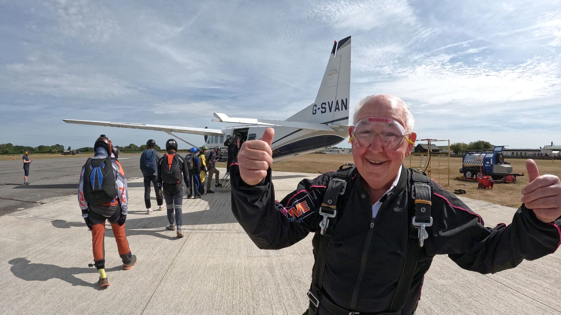 John Payne with with both thumbs up as he is about to board the air plane behind him.